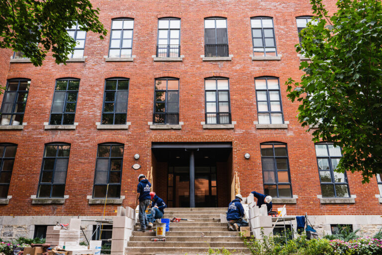 Des membres de l'équipe Atwill-Morin au travail, dans l'escalier extérieur au rez-de-chaussée d'un immeuble multirésidentiel. multi-residential building maintenance Toronto